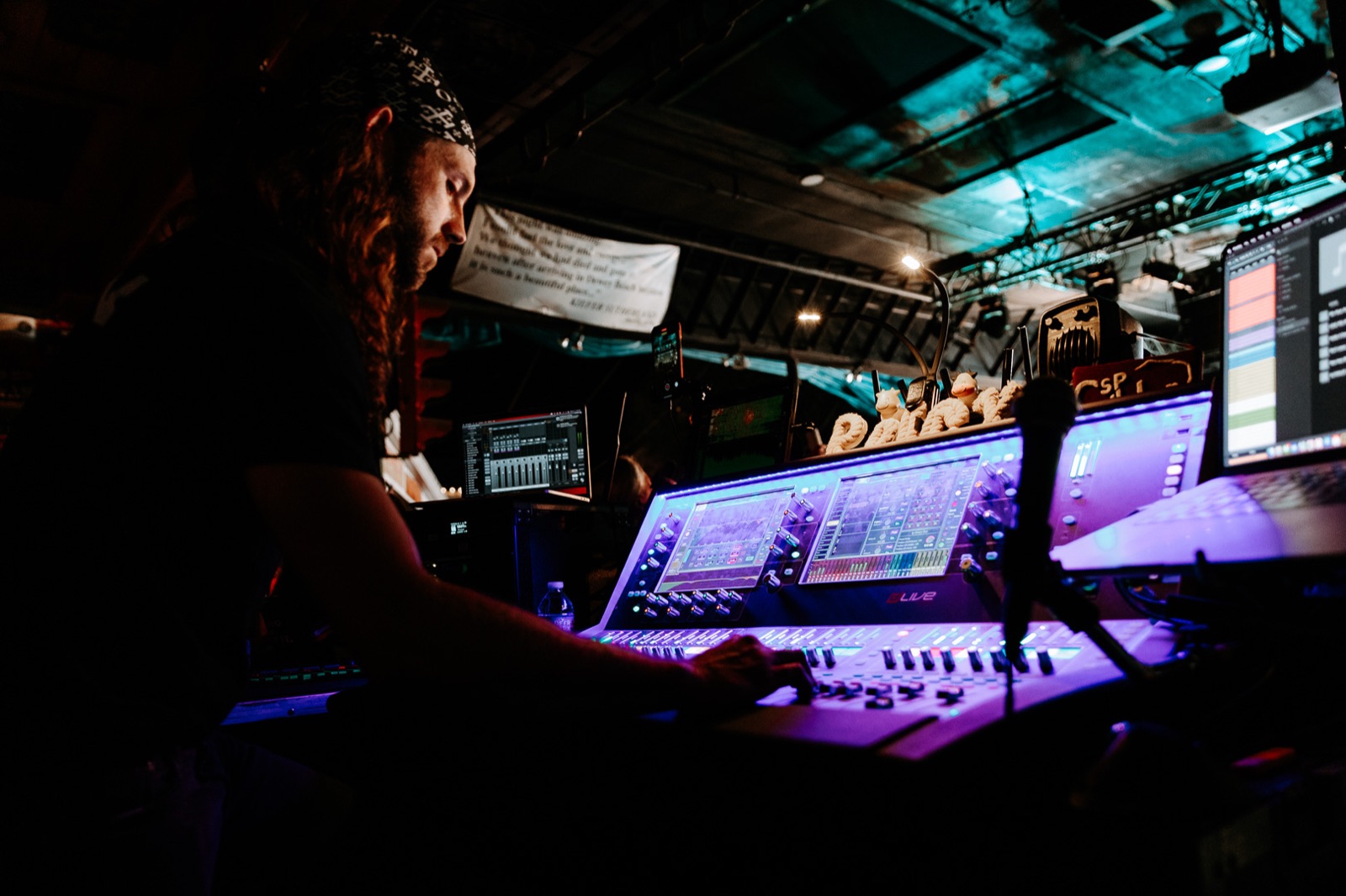 Engineer working a lighting console during the show, screens lit in the dark