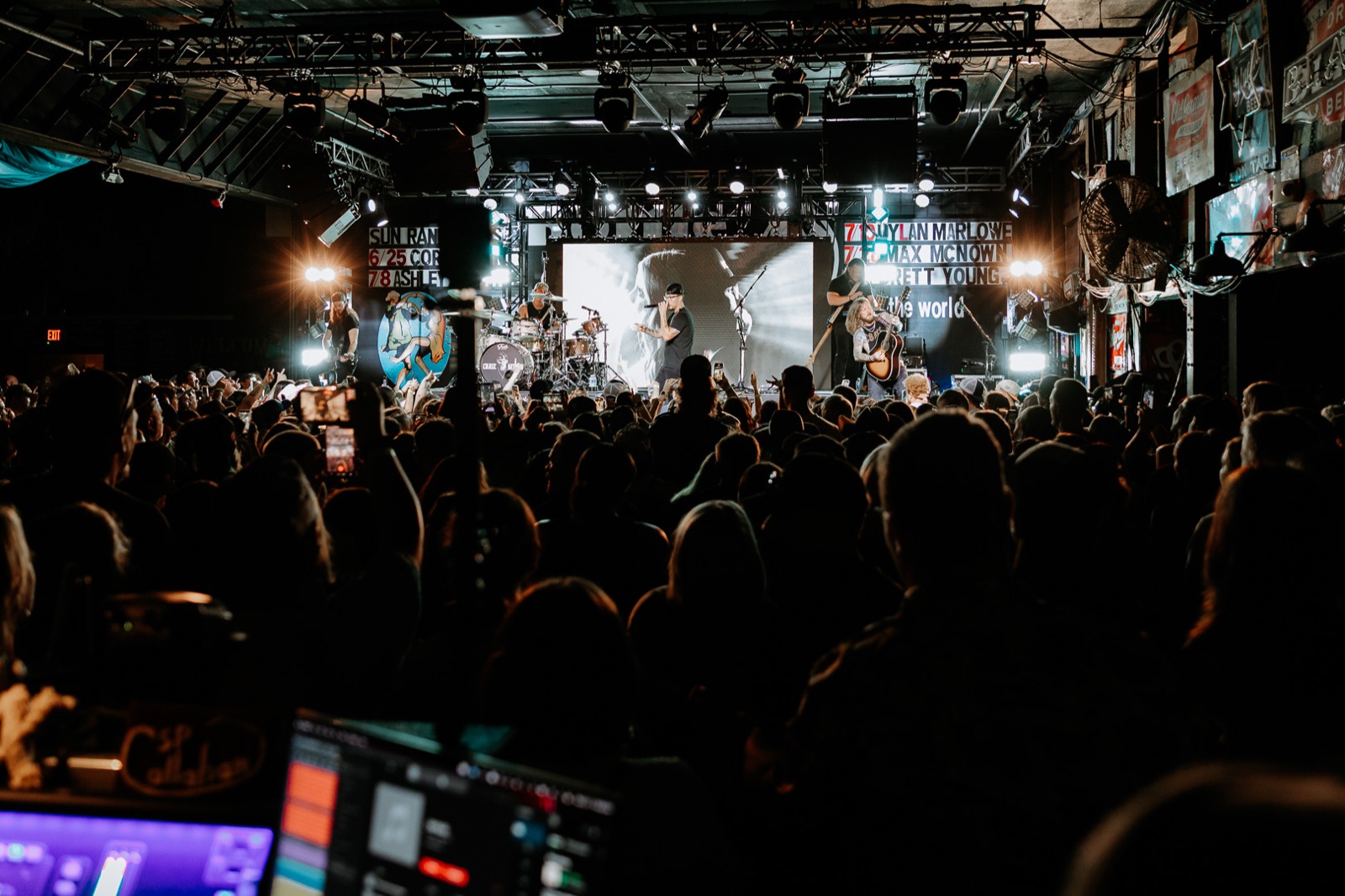 A full room during the show, stage lit beyond the crowd
