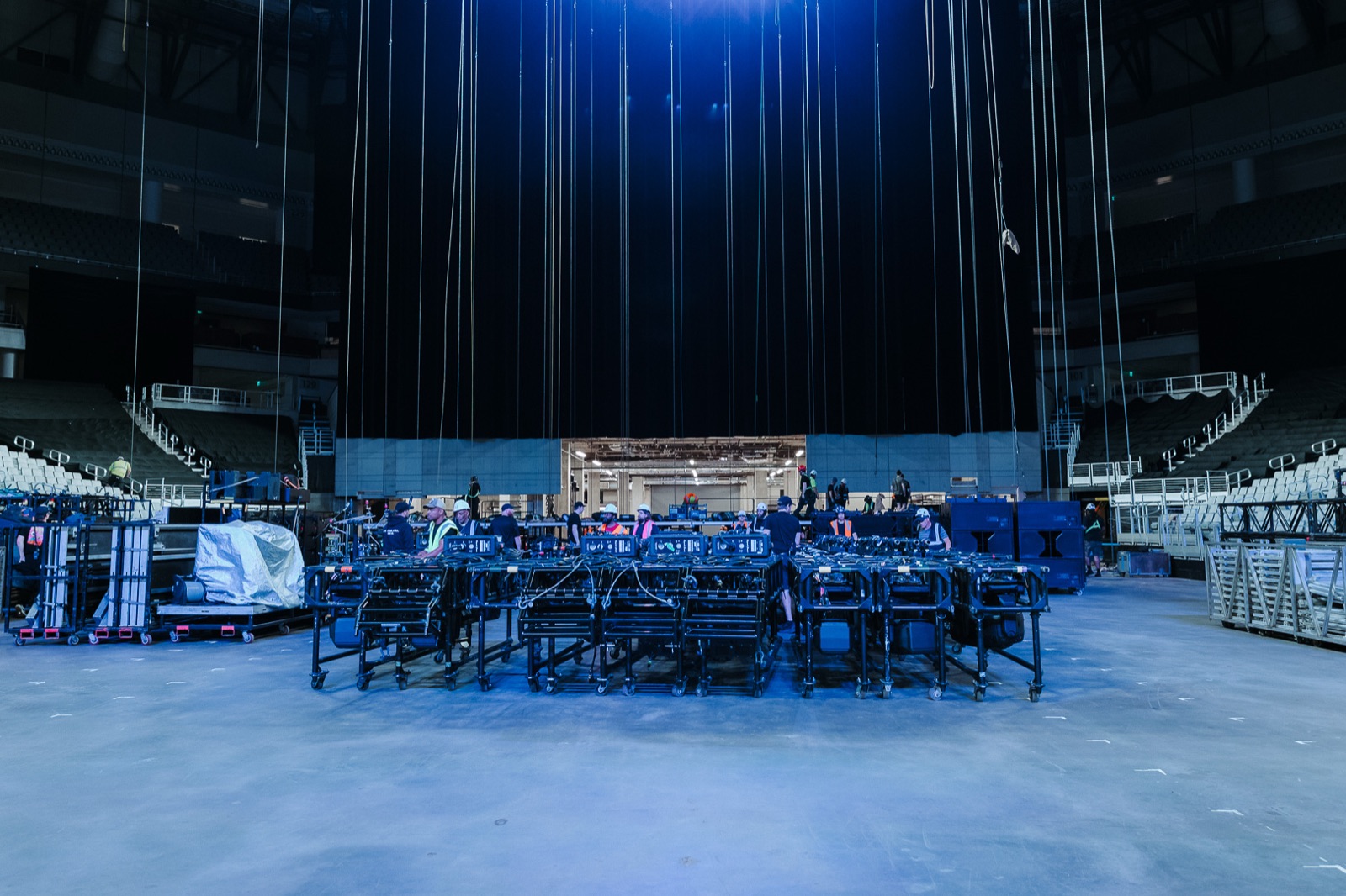 Empty arena floor before the build, staging carts under the rigging lines
