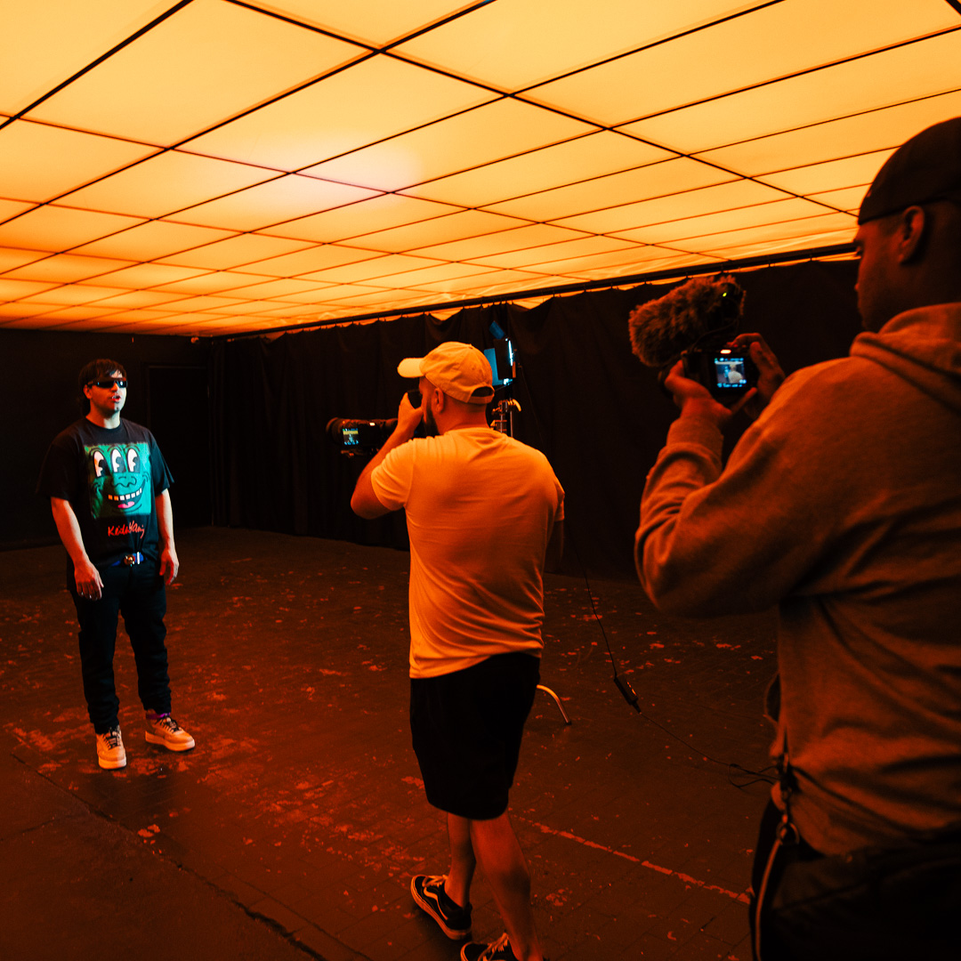 Operator rolling on a subject under a warm studio wash while a second camera covers the same setup